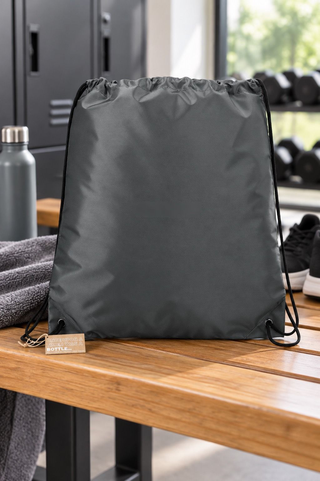 A graphite drawstring bag on a locker-room bench, undecorated.