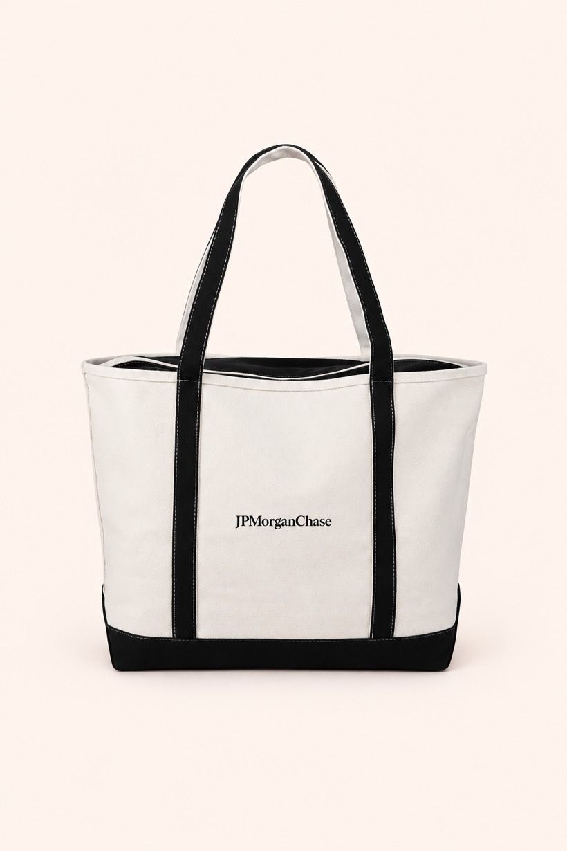 A natural canvas boat tote with black trim and a printed wordmark on the front panel.